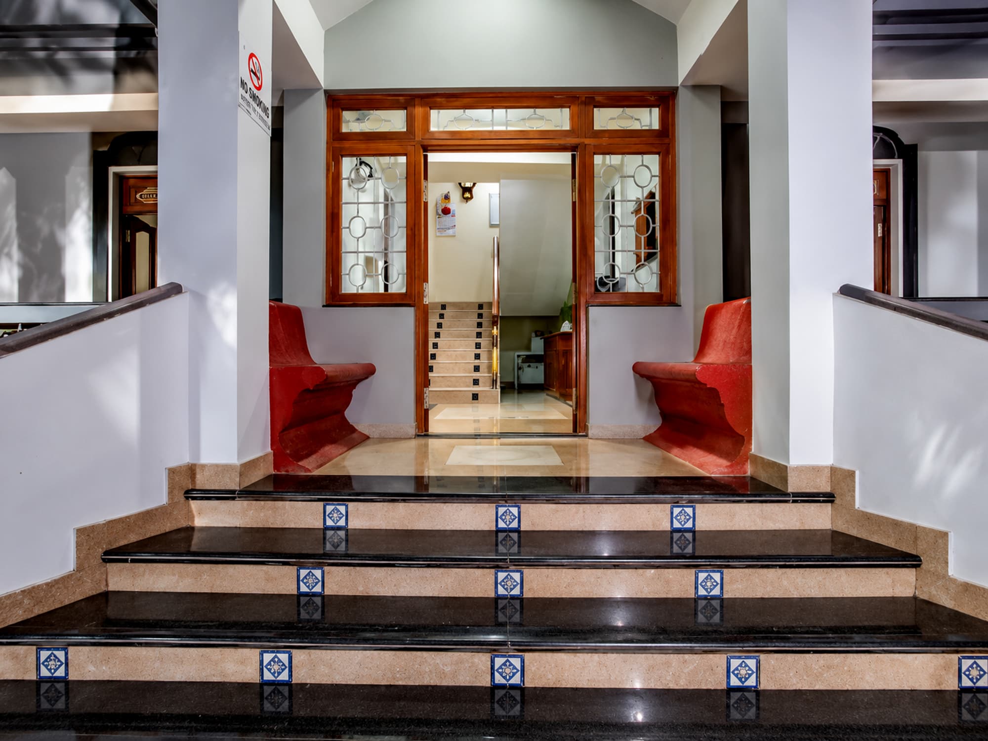 The entrance foyer at Misquita Comforts, with marble steps and carved wood-and-glass doors.