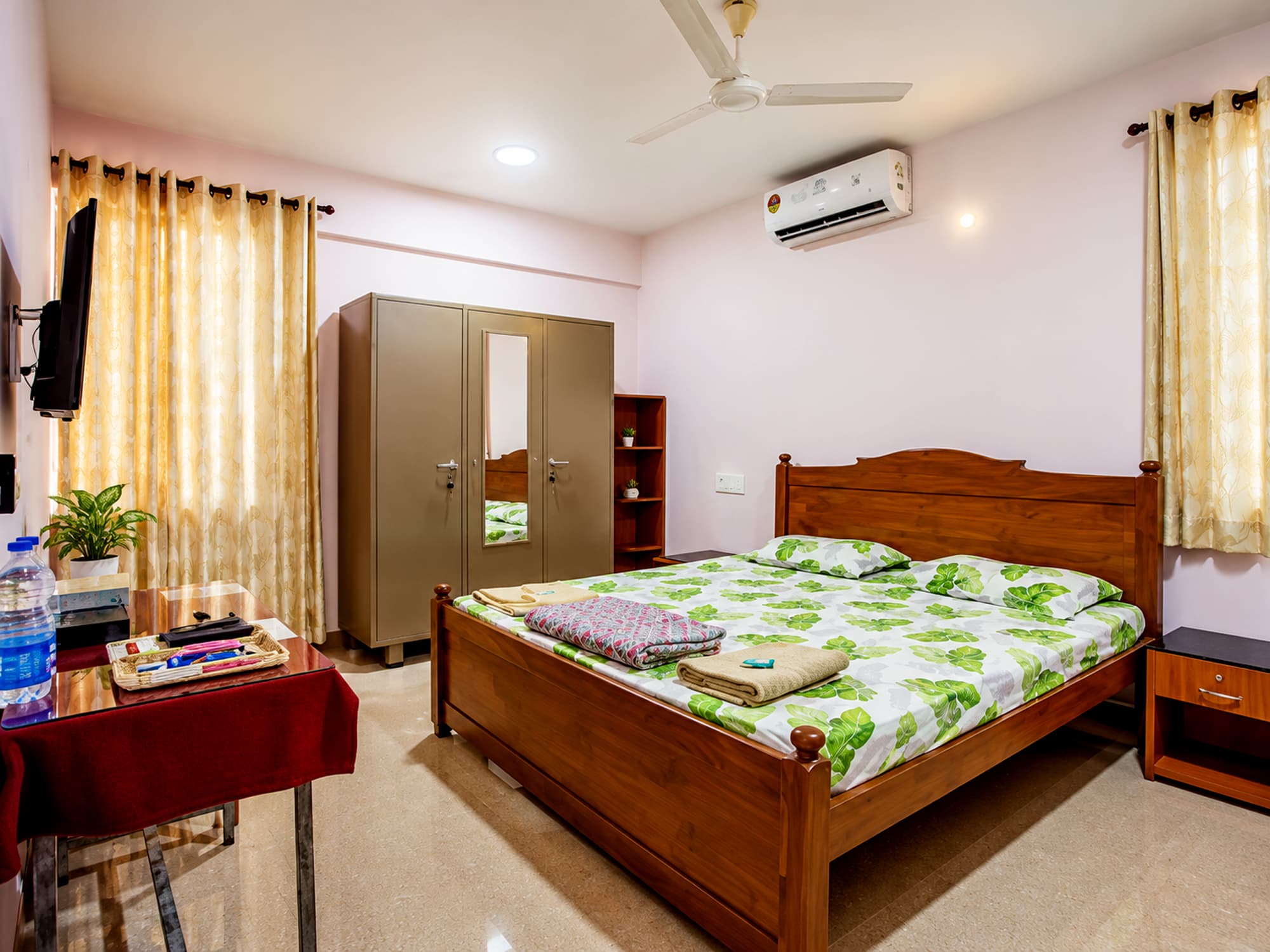 A studio bedroom at Misquita Comforts with a carved wooden bed, air conditioning and a TV.